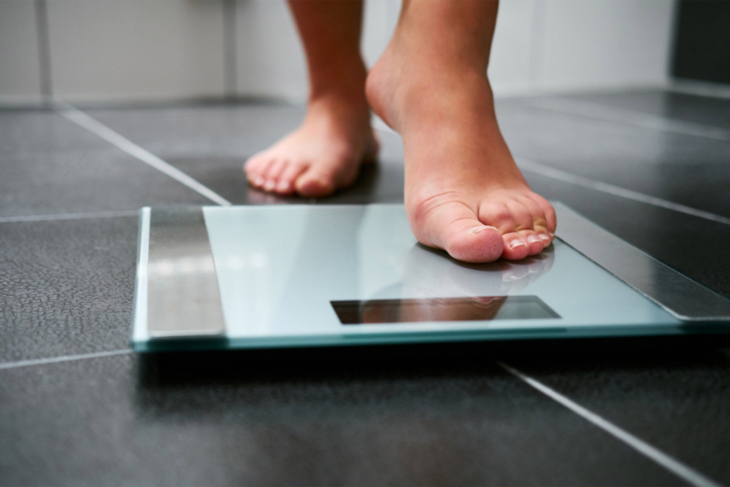 Person getting ready to weigh themselves on a scale.