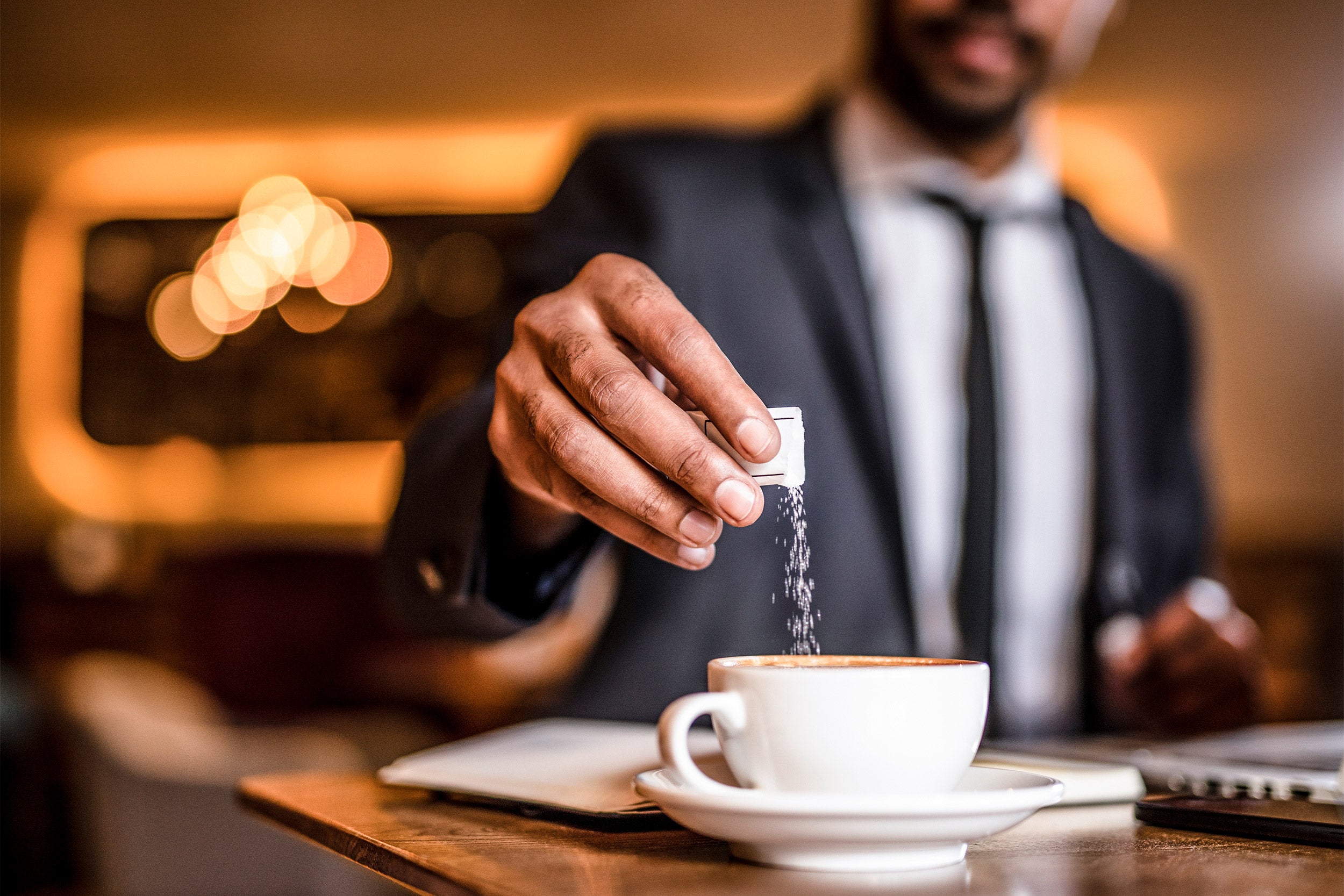 Man putting sugar in his coffee.